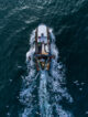 Fishing vessel boat floating in the blue sea, aerial top view from drone.