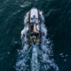 Fishing vessel boat floating in the blue sea, aerial top view from drone.