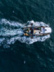 Fishing vessel boat floating in the blue sea, aerial view from drone.