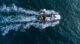 Fishing vessel boat floating in the blue sea, aerial view from drone.