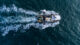 Fishing vessel boat floating in the blue sea, aerial view from drone.