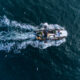 Fishing vessel boat floating in the blue sea, aerial view from drone.